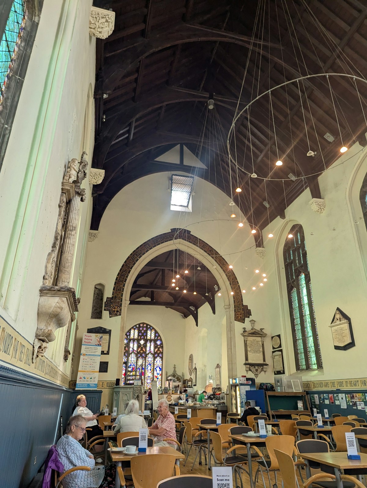 View of St Lawrence Café inside a converted church in Ipswich, showing customers seated at tables beneath tall arched ceilings and stained-glass windows